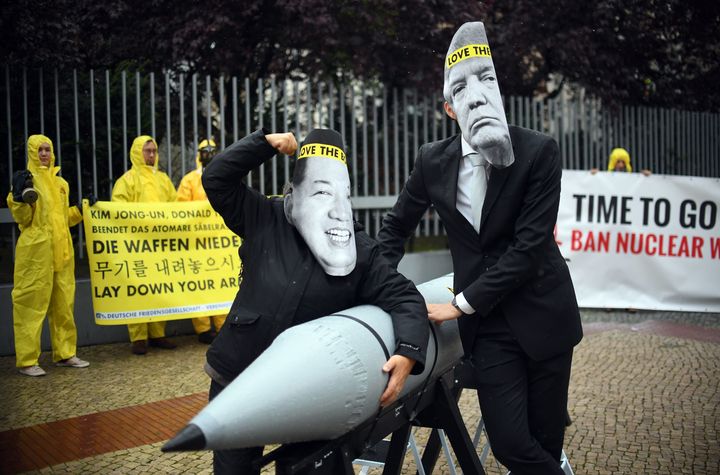 ICAN activists wear masks of Donald Trump and Kim Jong Un while posing with a mock missile in front of the embassy of Democratic People's Republic of Korea in Berlin, in September 