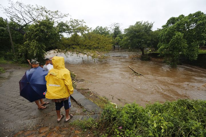Residents watch the swollen floodwaters of the river Masachapa 