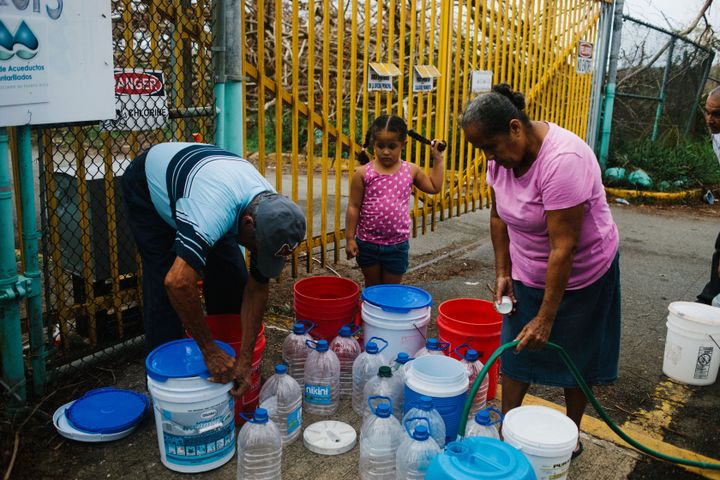 Residents fill containers with water at a center in Rio Grande, Puerto Rico, on Tuesday, Oct. 3, 2017.