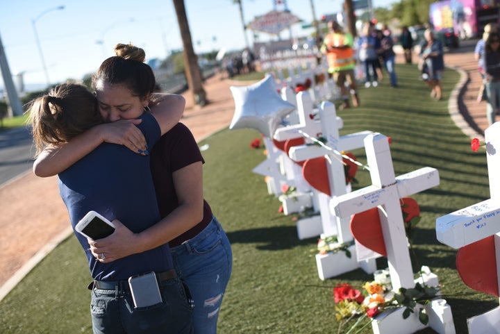 Melissa Gerber (L) and Sandra Serralde (R) comfort each other beside 58 white crosses.