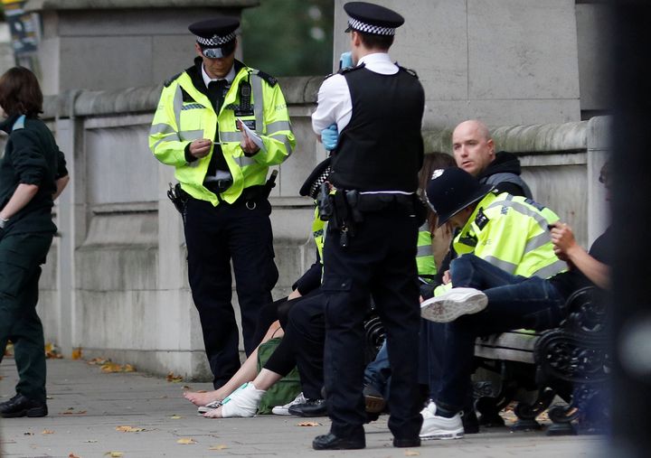 Police officers stand next to a person with a bandaged ankle near the Natural History Museum in London on Oct. 7.
