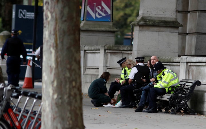 Police officers stand next to a person with a bandaged ankle