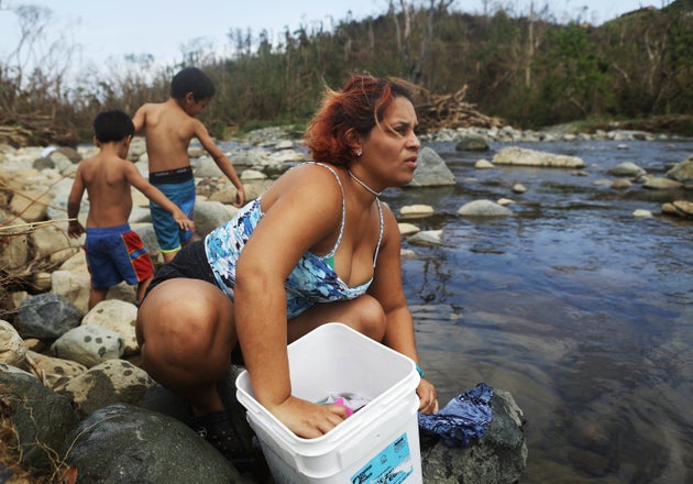 Maria Chiclano, who has no running water or power in her home, washes clothes with her sons in the Espiritu...