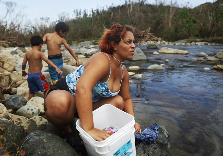 Maria Chiclano, who has no running water or power in her home, washes clothes with her sons in the Espiritu Santo river during heavy rains, more than two weeks after Hurricane Maria devastated Puerto Rico.