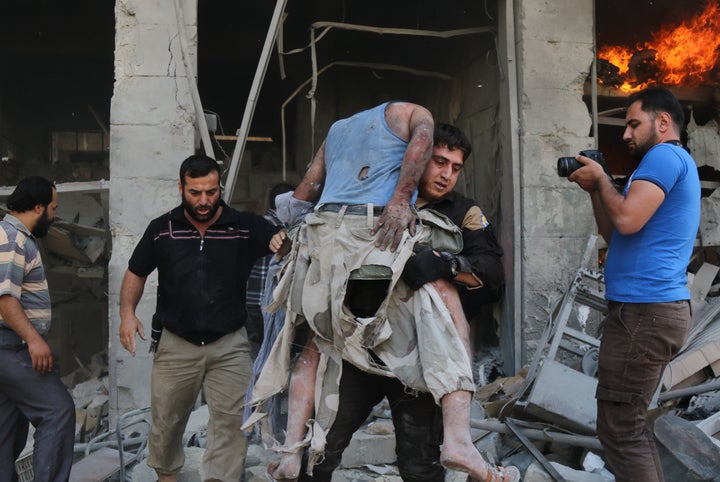 A member of the Syrian Civil Defense, also known as White Helmets, carries a victim following the airstrike at the Maaret al-Numan market.