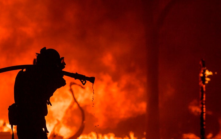 A firefighter pulls a hose in front of a burning house in the Napa wine region of California on Oct. 9, 2017.