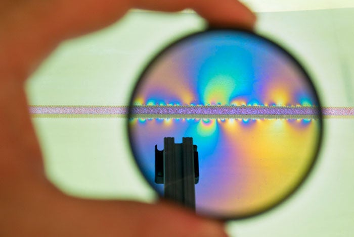 <p>Researchers at Los Alamos National Laboratory have developed a two-dimensional tabletop simulator that models the buildup and release of stress along an artificial fault. In this image, the simulator is viewed through a polarized camera lens, photo-elastic plates reveal discrete points of stress buildup along both sides of the modeled fault as the far (upper) plate is moved laterally along the fault.</p>