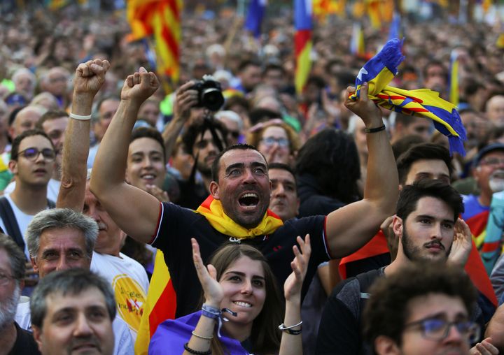 People react towards a giant screen showing events inside the Catalan regional parliament during a pro-indpendence rally outside the parliament in Barcelona