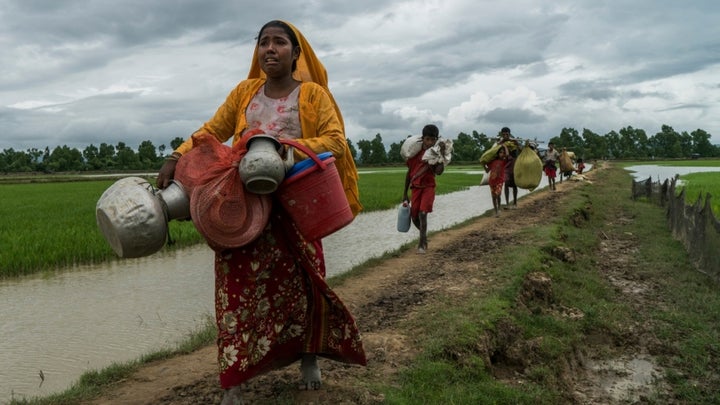 Senwara, a Rohingya refugee, cries as she arrives in Whaikhyang, Bangladesh, after walking two days from Myanmar with her father and son. 