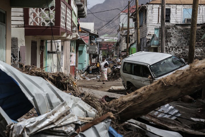 <p> A woman walks in the street of Roseau, capital of Dominica, which is struggling to overcome the severe impact of two category 5 hurricanes which tore through the region in September 2017. </p>
