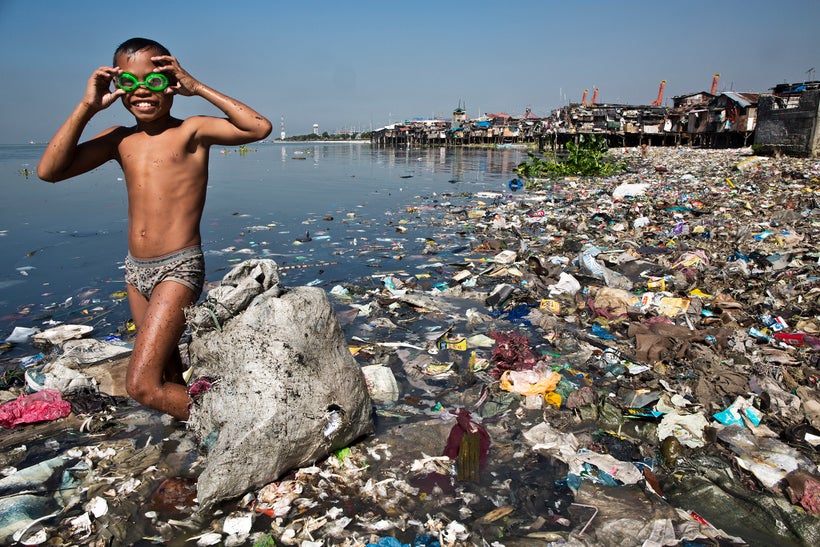 Rodello Coronel, age 13, picks through trash on the beach for recyclable plastic he can sell to support his family in Manilla