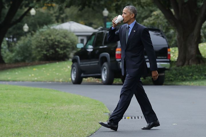 Barack Obama takes a sip of tea as he walks across the South Lawn in 2016.