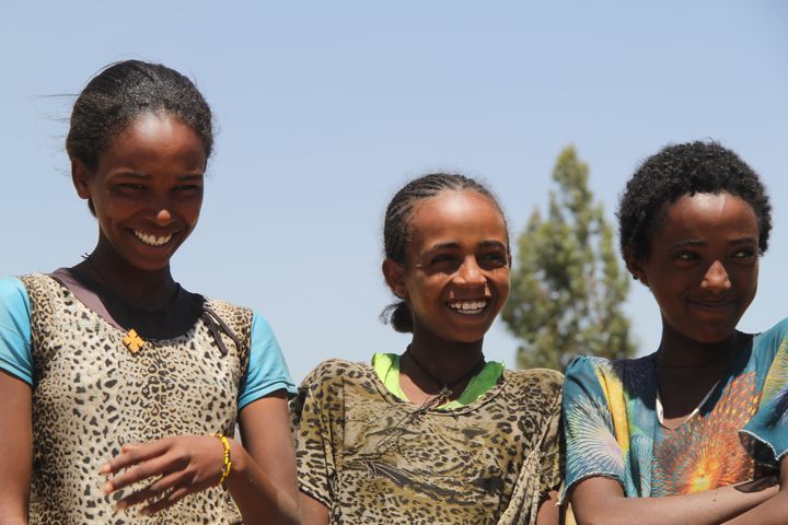 Nigisti and two of her friends smile as they watch their schoolmates wash their hands.