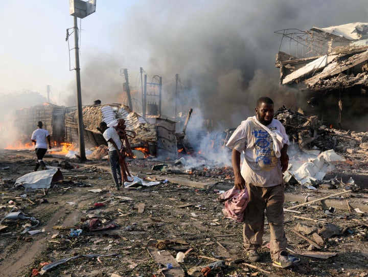 Civilians walk at the scene of an explosion in KM4 street in the Hodan district of Mogadishu, Somalia October 14, 2017.