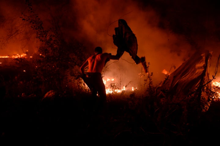 A man attempts to subdue wildfire flames in Vigo, northwestern Spain, October 15, 2017.