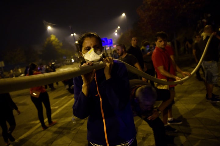 People carry a hose to help fighting a wildfire in Vigo.