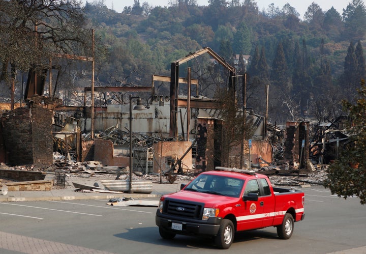 A firefighting crew drives pass a business destroyed in wildfire that tore through Santa Rosa, California, U.S., October 15,