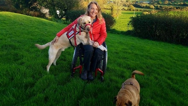 Chris Slavin of Danvers, Massachusetts, with her 3-year-old service dog, Earle. Massachusetts is considering a bill that would crack down on people who misrepresent their pets as service dogs. Nineteen other states have adopted similar measures.