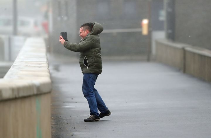 People take selfies in waves and high wind at Lahinch in County Clare