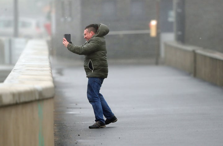 People take selfies in waves and high wind at Lahinch in County Clare