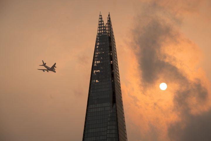 <strong>A plane flies past the Shard in central London, as the sky takes on an unusual orange colour caused by Storm Ophelia</strong>