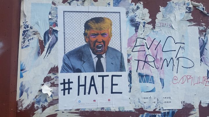 In the months leading up to the presidential election on the exterior of a building in the Chelsea neighborhood of Manhattan a poster with an image of Donald Trump is posted with the caption '# Hate'. Someone has written on top of old peeling posters besides it 'Evict Trump'. 