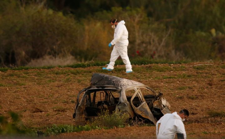 Forensic experts walk in a field after a powerful bomb blew up a car and killed investigative journalist Daphne Caruana Galizia in Bidnija, Malta.