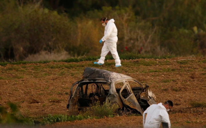 Forensic experts walk in a field after a powerful bomb blew up a car and killed investigative journalist Daphne Caruana Galizia in Bidnija, Malta.