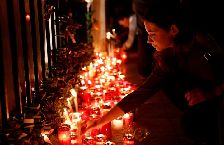 A woman places a candle on the Love monument during a silent candlelight vigil for Daphne Caruana Galizia.