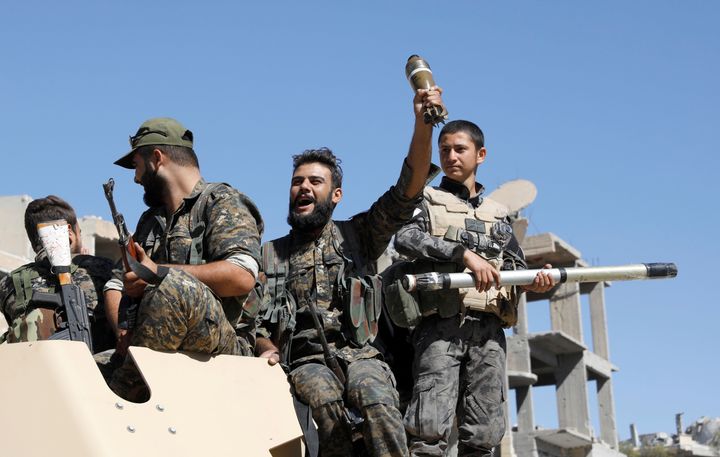 Fighters of Syrian Democratic Forces jubilate aboard an armoured fighting vehicle after Raqqa was liberated from the Islamic State militants, in Raqqa, Syria.