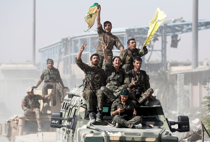 Syrian Democratic Forces (SDF) fighters ride atop of military vehicles as they celebrate victory in Raqqa, Syria.