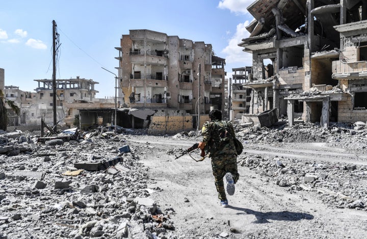 A member of the Syrian Democratic Forces takes cover from sniper shots near the central hospital of Raqqa on Oct. 1.