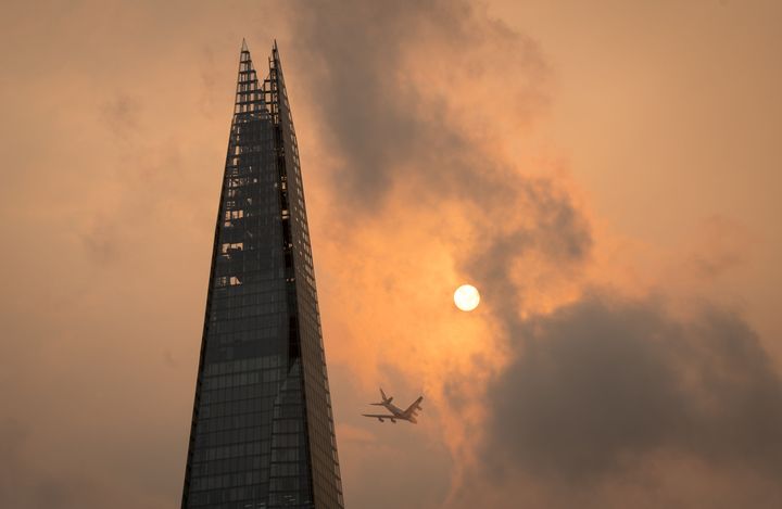 A plane flies past the Shard in central London, as the sky takes on an unusual orange colour caused by Storm Ophelia on Mond
