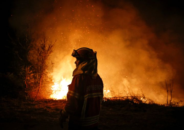 A firefighter stands silhouetted against the flames in Cabanoes near Lousa, Portugal, on Oct. 16, 2017.