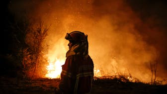 A firefighter is seen near flames from a forest fire in Cabanoes near Lousa, Portugal,  October 16, 2017.  REUTERS/Pedro Nunes