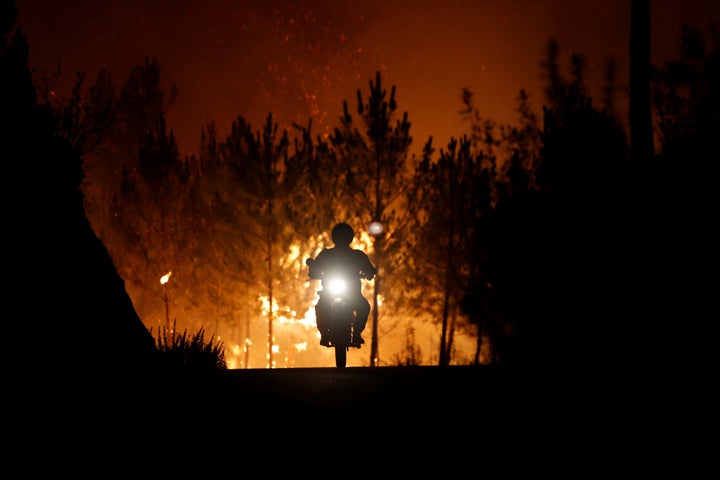 A firefighter rides a motorbike away from the fire around the village of Macao, near Castelo Branco, Portugal, on July 26, 2017.