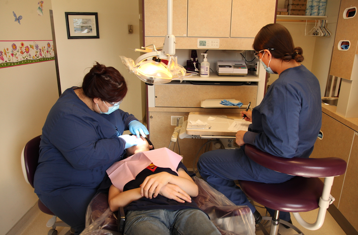 Dental Therapists, Elsie Pelawook and Savannah Bonorden, performing dental work on a patient. 