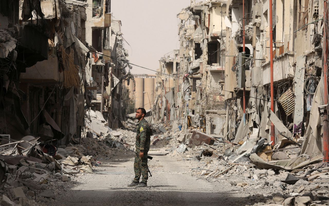 A fighter from the Syrian Democratic Forces (SDF) stands next to debris of damaged buildings in Raqqa, Syria, on Sept. 25, 2017.