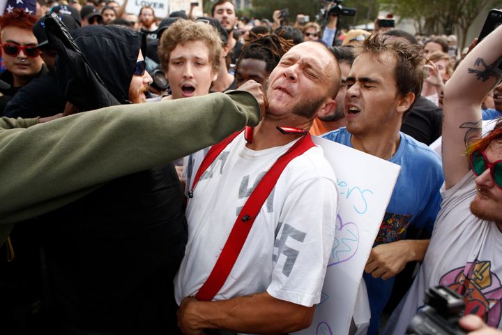 A man wearing a shirt with Nazi swastikas on it is punched by an unidentified member of the crowd near where white supremacist Richard Spencer spoke on Thursday at the University of Florida in Gainesville.