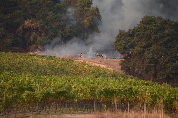 Firefighters protect a vineyard in Santa Rosa, in Sonoma County, on Oct. 11. Damage at vineyards has also caused job losses. Particularly hard hit are immigrant families.