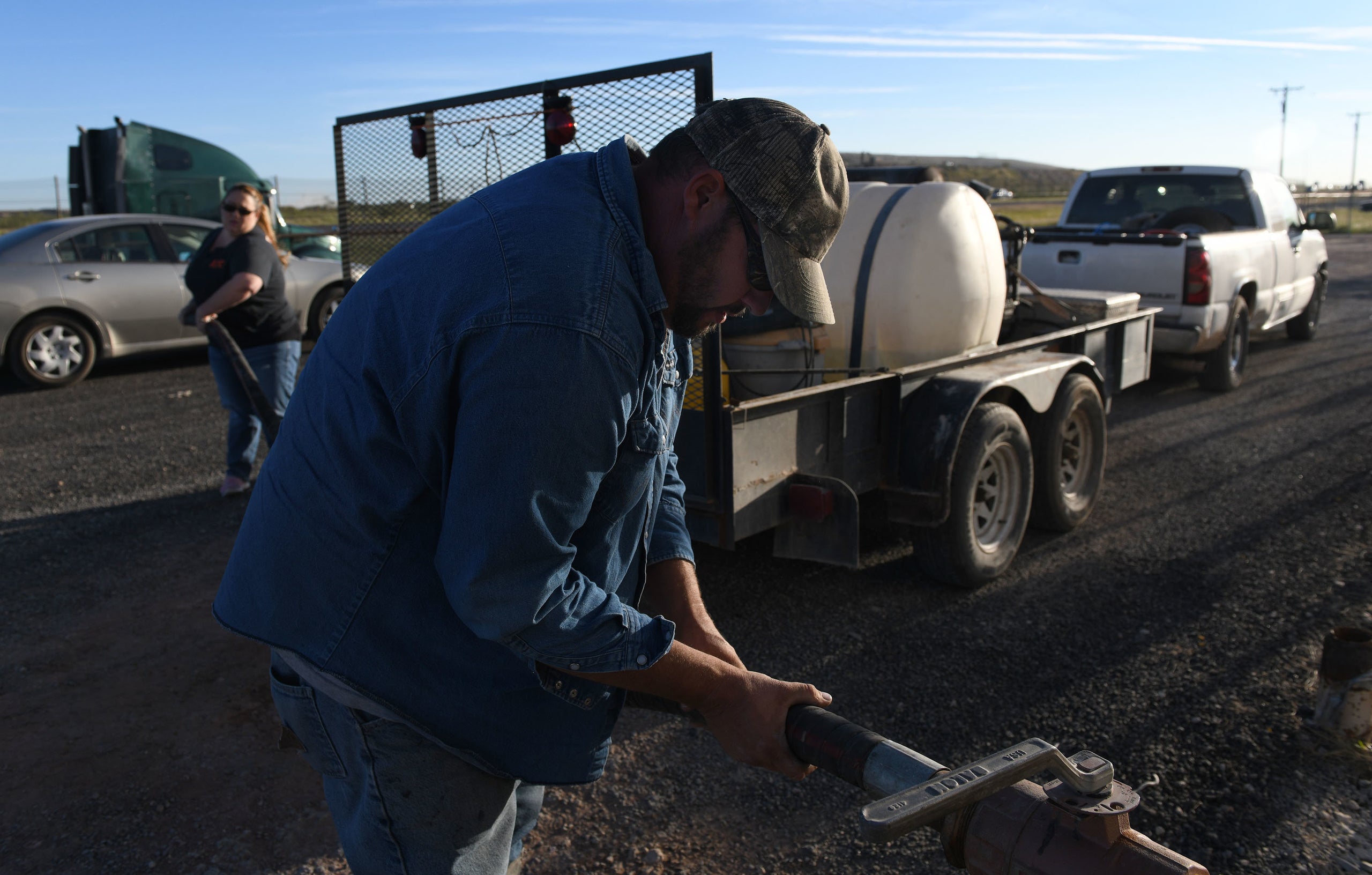 Ray Smith and his wife, Tara, hook up a hose at a water distributing station to fill their pressure-washer tank.