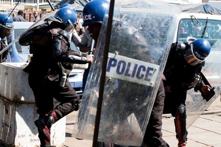 Police surround an activist lying on the ground at Harare Central Police Station during a protest in August, 2016 amid anti-government marches in Zimbabwe