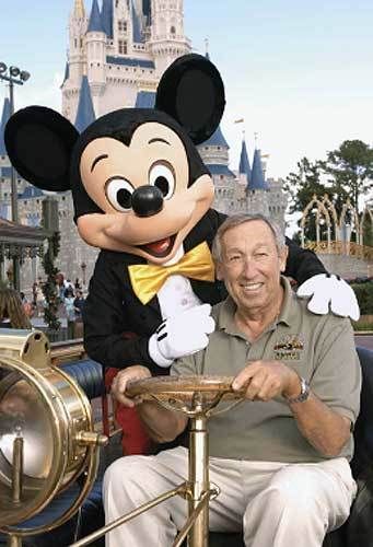 <p>Roy E. Disney poses for a picture with Mickey Mouse in front of Cinderella Castle at WDW’s Magic Kingdom</p>