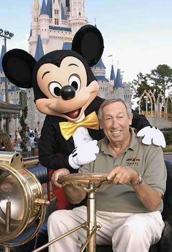 Roy E. Disney poses for a picture with Mickey Mouse in front of Cinderella Castle at WDW’s Magic Kingdom