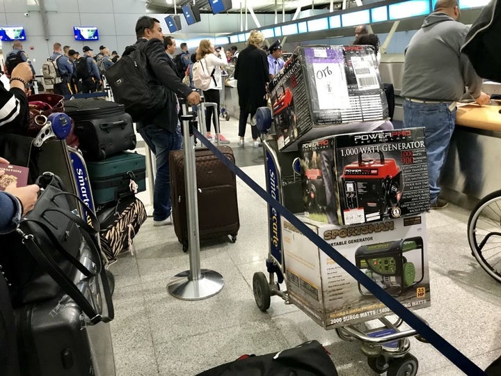 Travelers at JFK Airport in New York City prepare to check newly purchased generators as baggage for flights to San Juan Puer