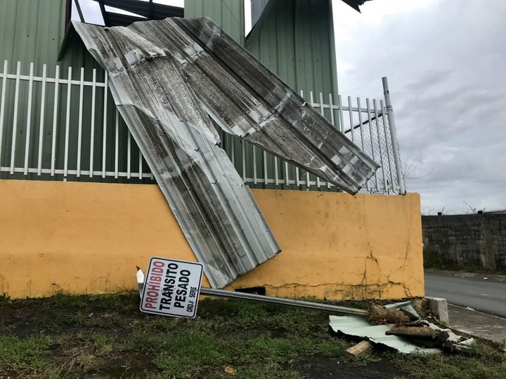 A downed no trespassing sign lays on the grass in front of a building damaged by Hurricane Maria in Bayamon, Puerto Rico.