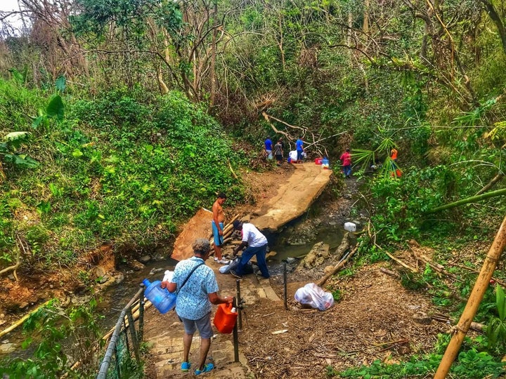 People bathe in and collect water from a stream in Bayamon, Puerto Rico.