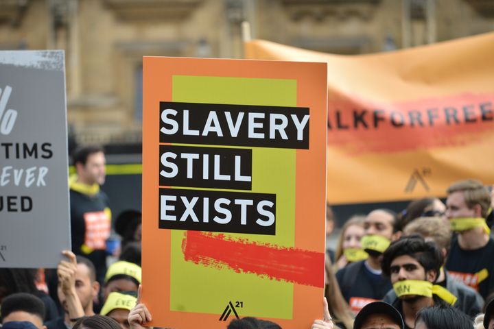 People marching against modern slavery through London wearing face masks representing the silence of modern slaves in forced labour and sexual exploitation.