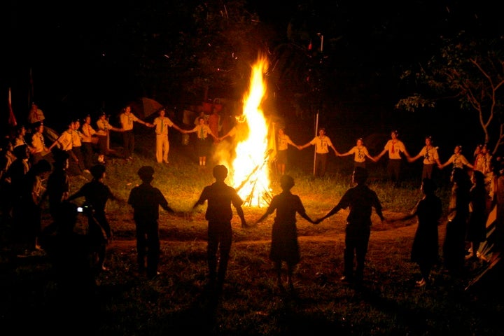 <p>Cambodian boy and girl scouts join hands as they dance around a bonfire in 2008.</p>