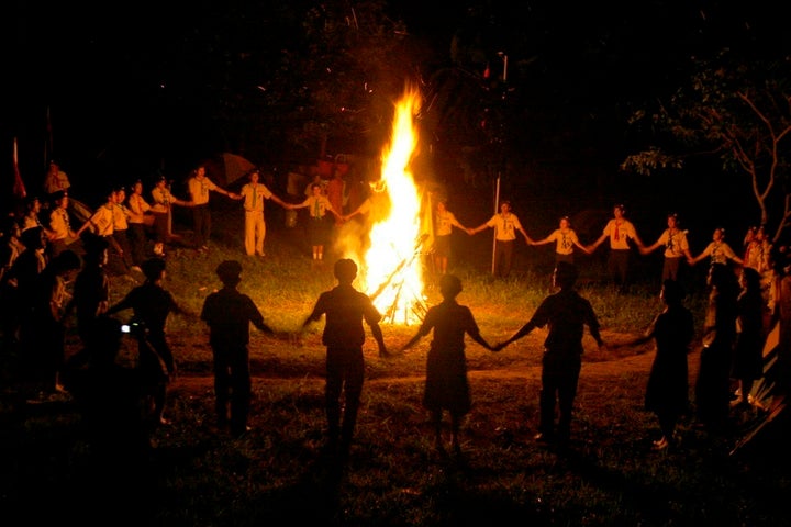 Cambodian boy and girl scouts join hands as they dance around a bonfire in 2008.